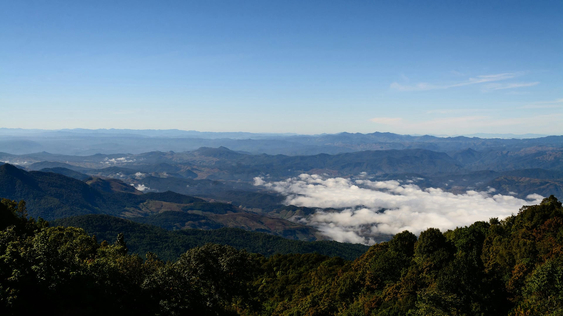 Layered ridgelines of the Doi Inthanon range above a sea of cloud, seen from the summit at sunrise